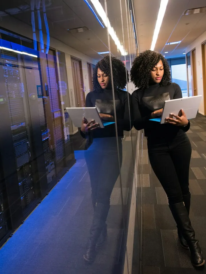 IT engineer checking systems on a tablet beside a server room